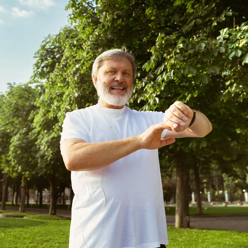 An active older man checking his fitness watch outdoors